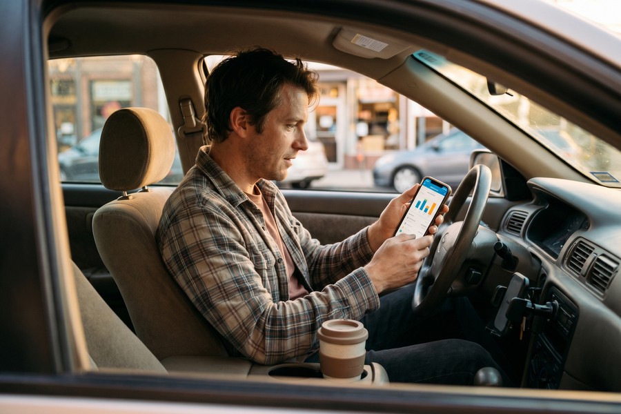 Rideshare driver using a ride-share app dashboard to track weekly earnings totals